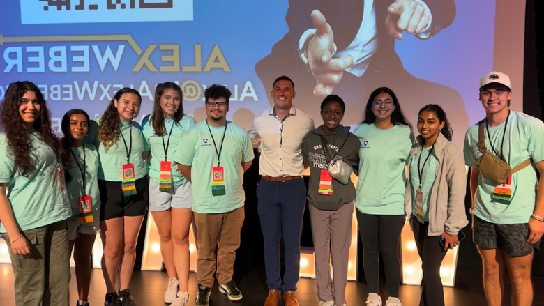 students smiling on a stage inside an auditorium 